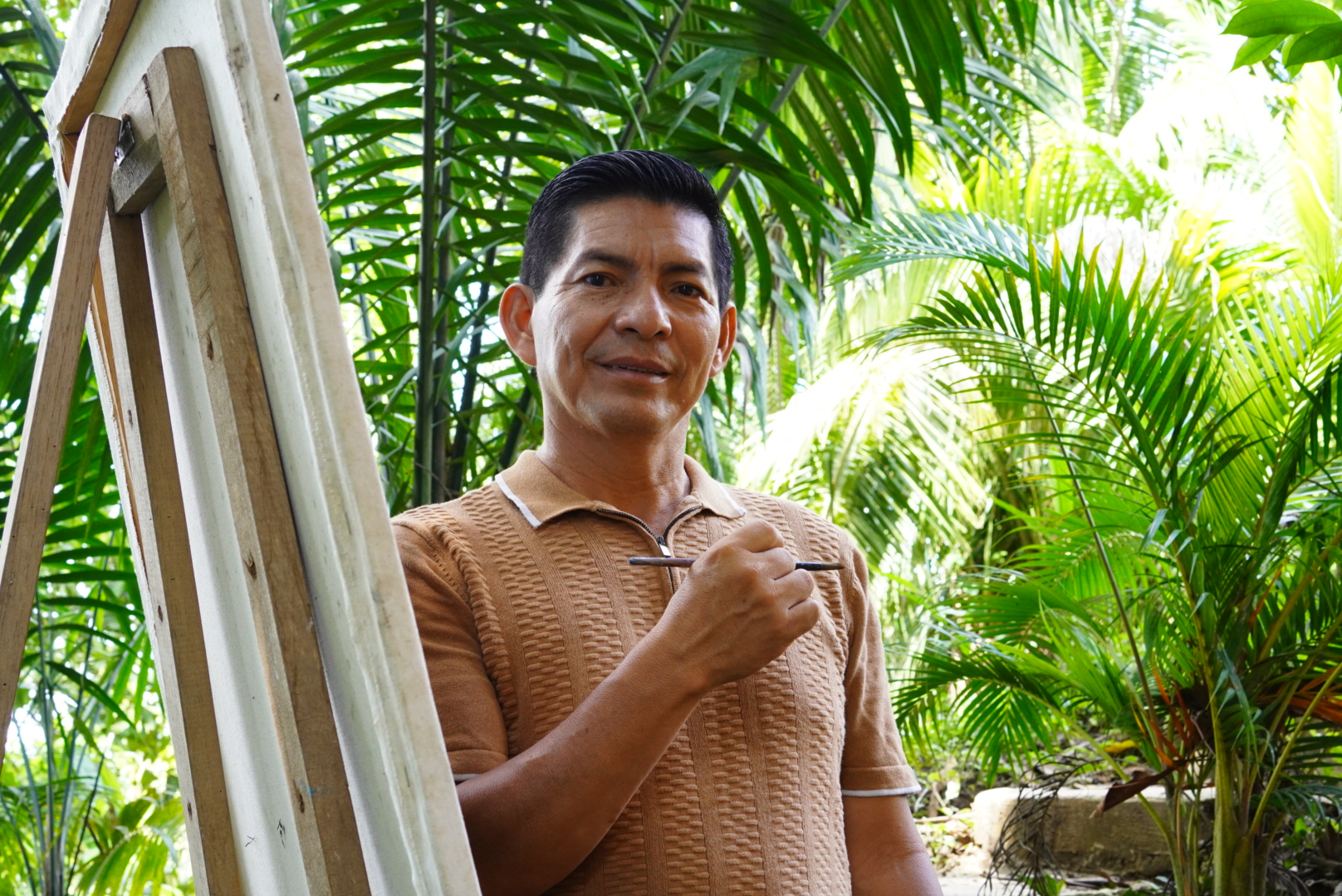 Moisés Llerena painting at his easel in the Amazon garden